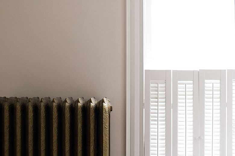 Antique Gold Cast Iron Radiator, Palest Blush Pink Walls, White Trim and Wooden Shutters